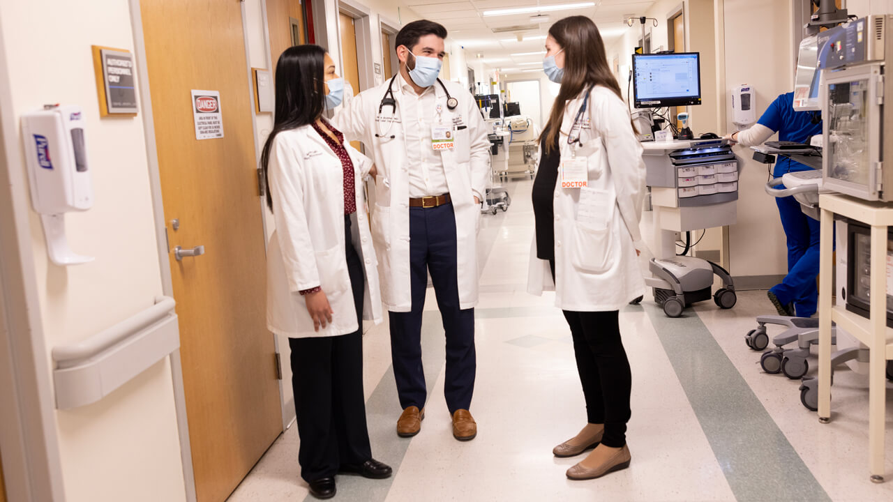 Doctors discuss in the hallway of a healthcare facility.