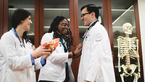 Three students practice clinical skills in the medical bone room